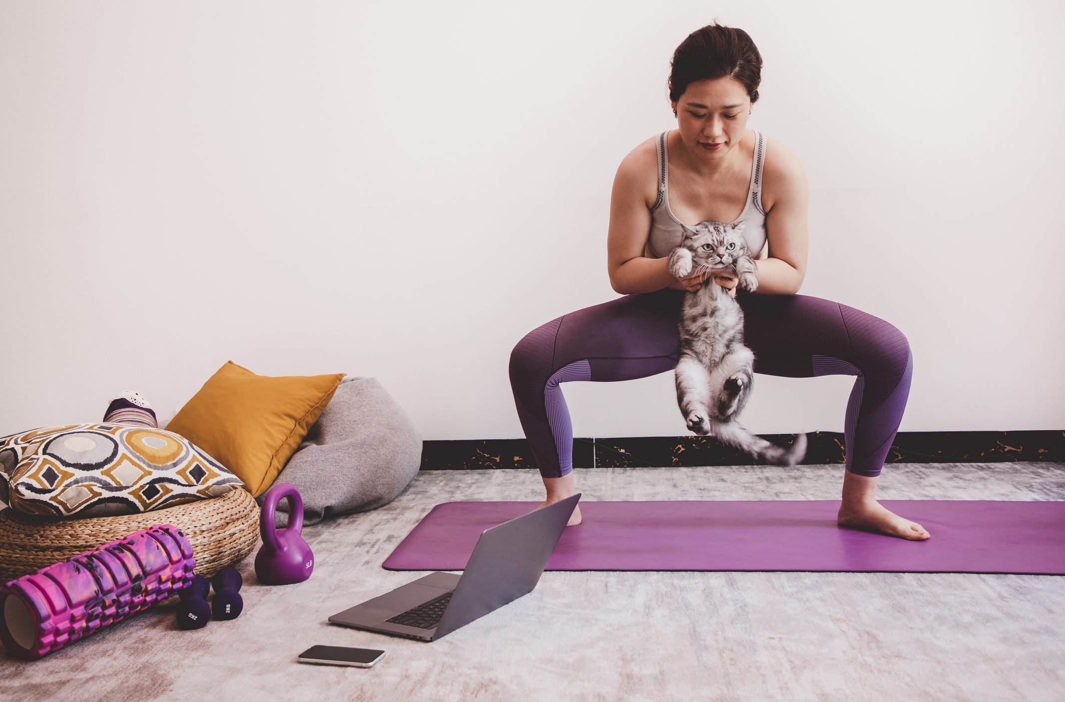 Asian woman doing squat while holding her cat