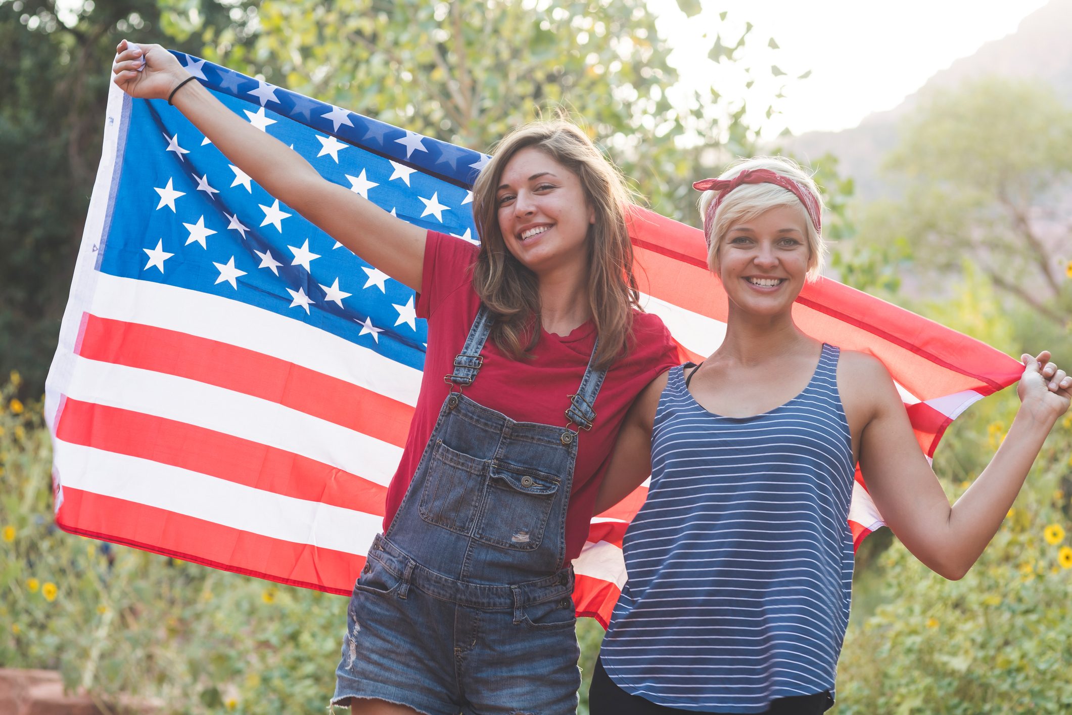 Two friends drape themselves in an American flag outside