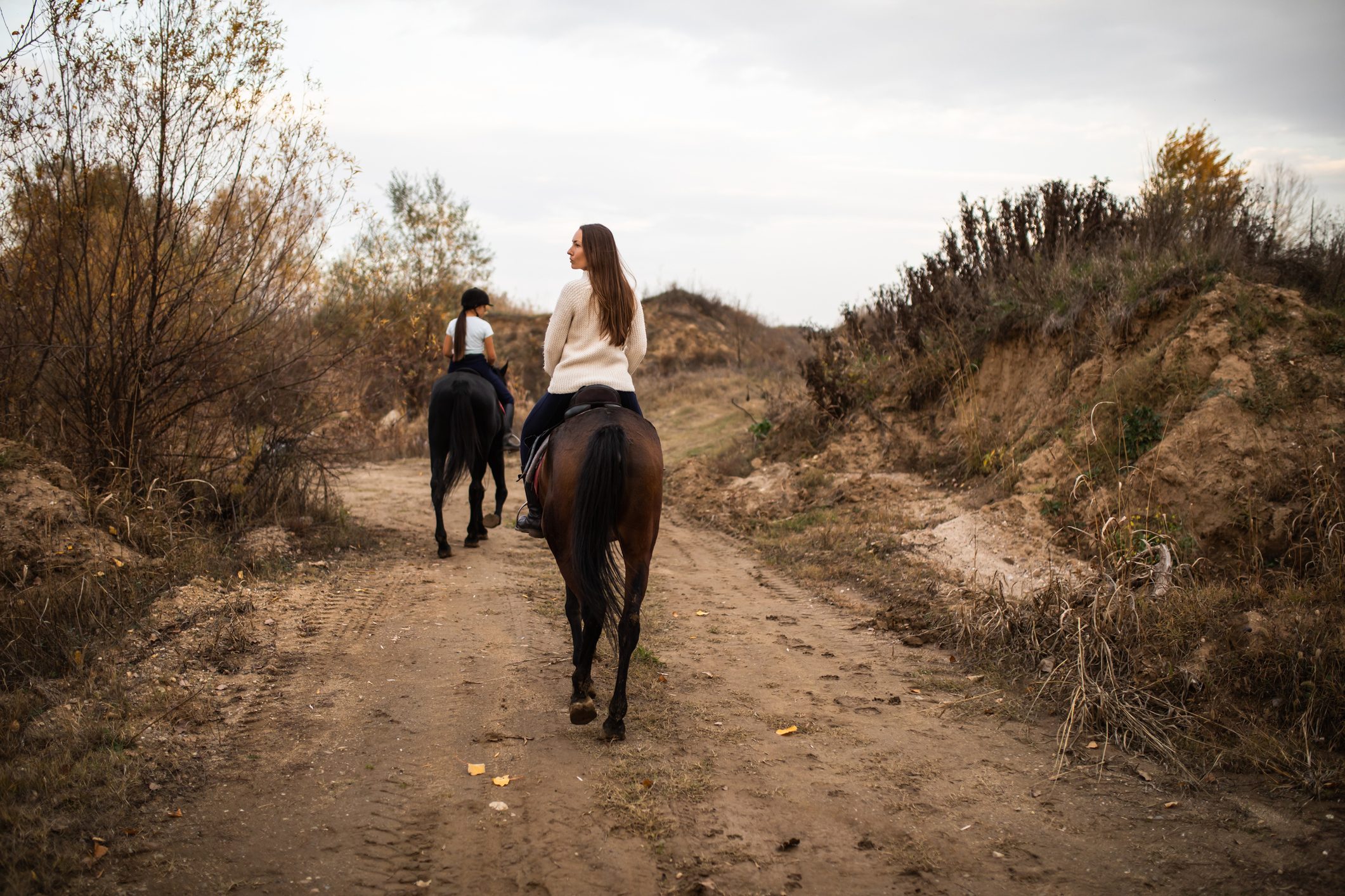 Two young women horseback riding in the countryside