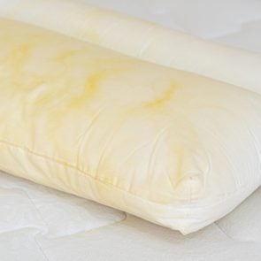 Pillow with yellow stains atop a mattress