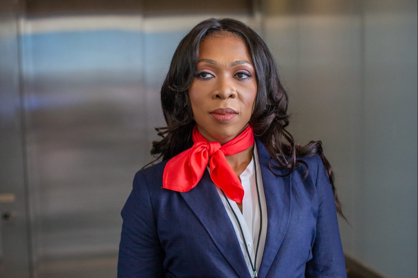 Airline flight attendant stands in airport elevator.
