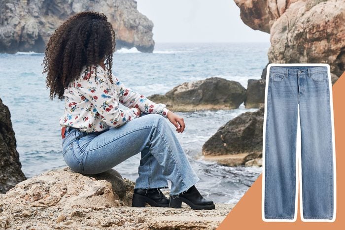 woman wearing jeans sitting on rocks looking out at the ocean