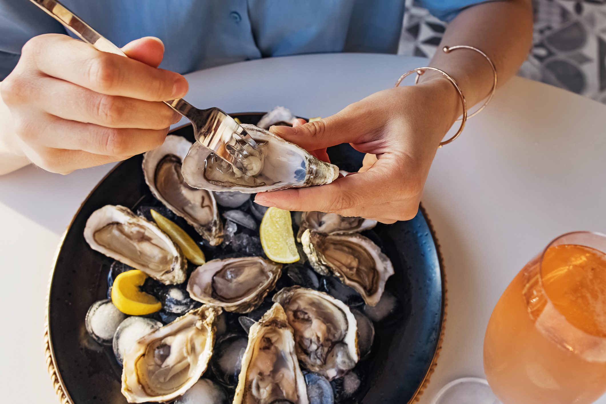Woman eating fresh oysters with lemon