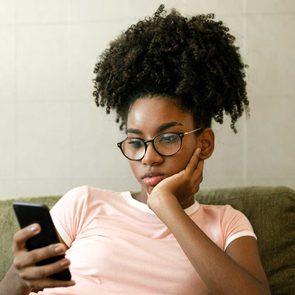 Teenage Girl Using Smart Phone On Couch