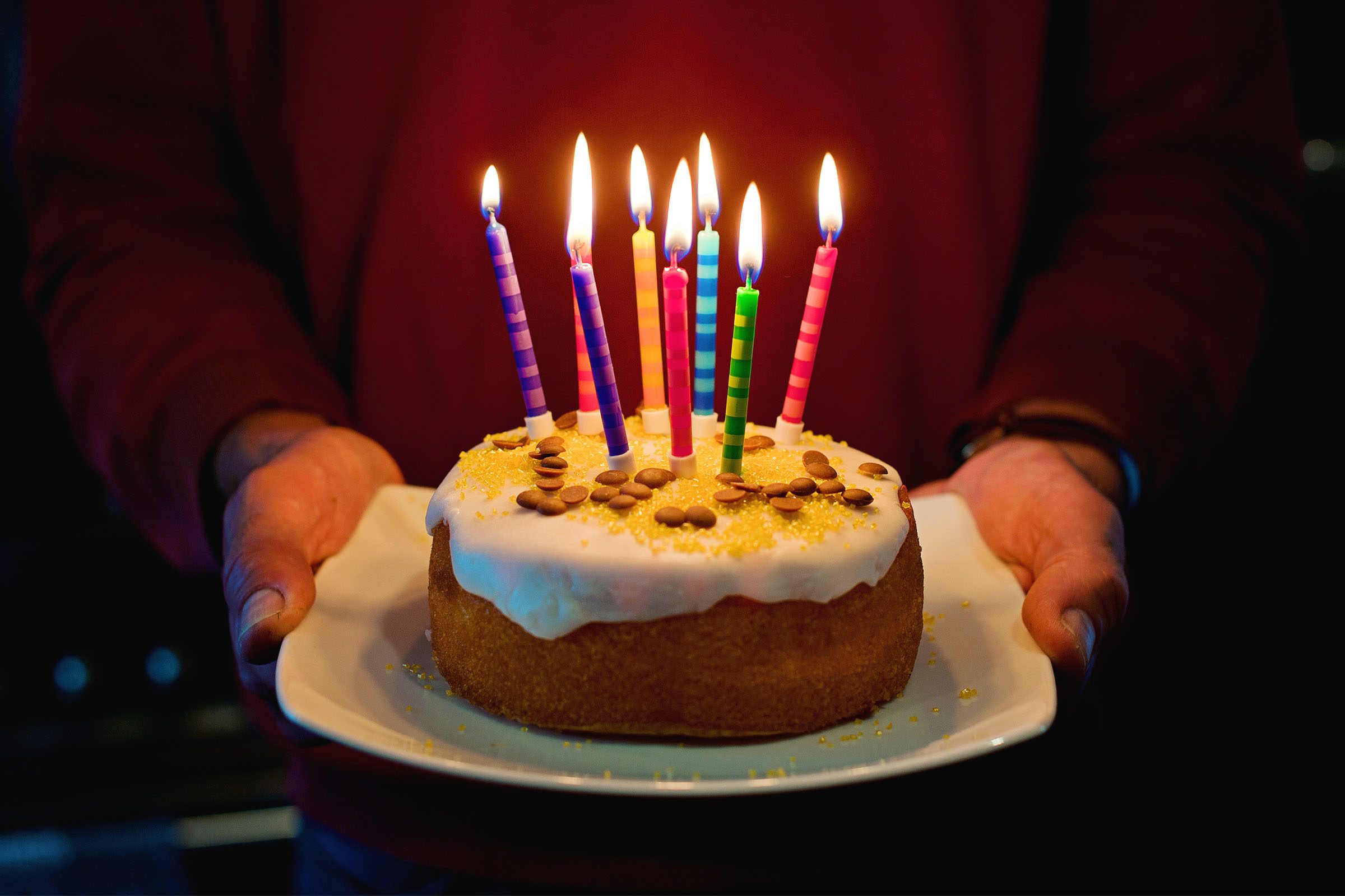 Man, birthday cake, 8 glowing coloured candles