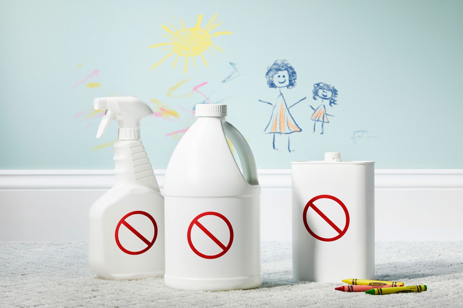 three all-white cleaning supplies bottles with "no" signs on floor in front of crayon markings on wall
