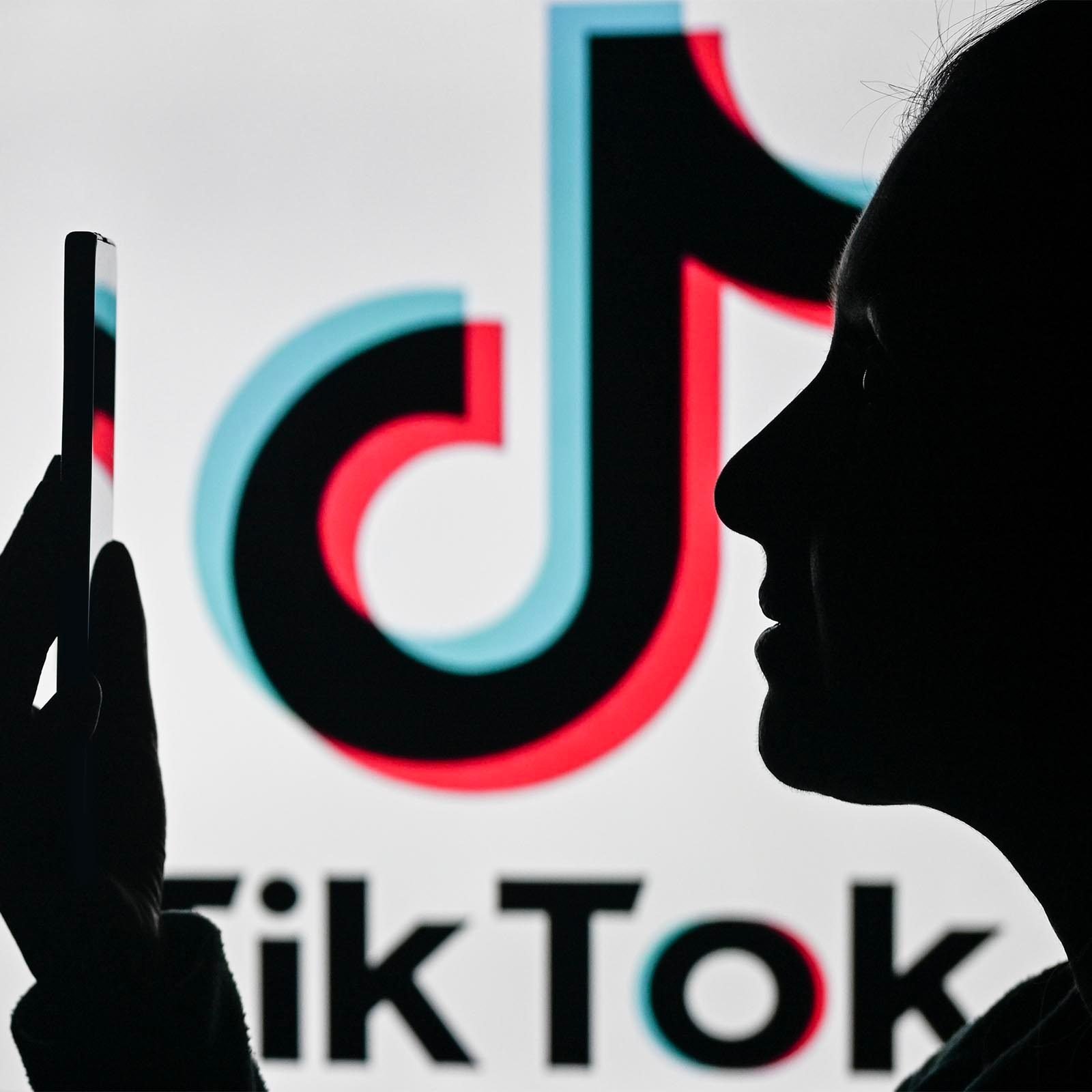 Woman looking at phone in front of Tiktok logo