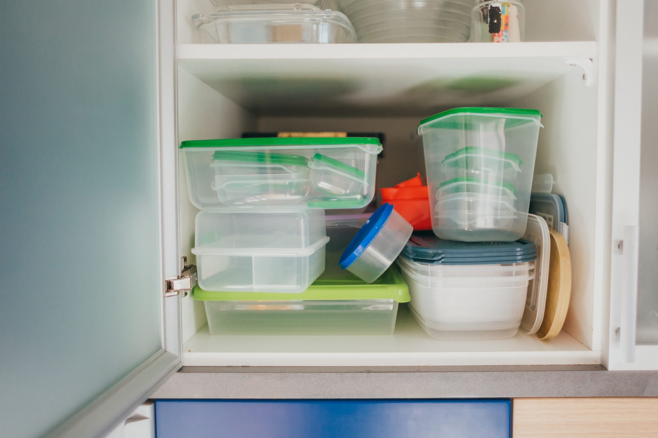 Kitchen cabinet full of food plastic containers and lunch boxes