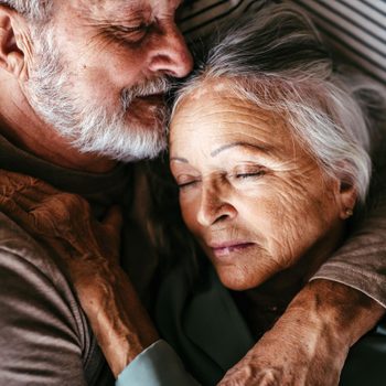 Older couple embracing while lying down