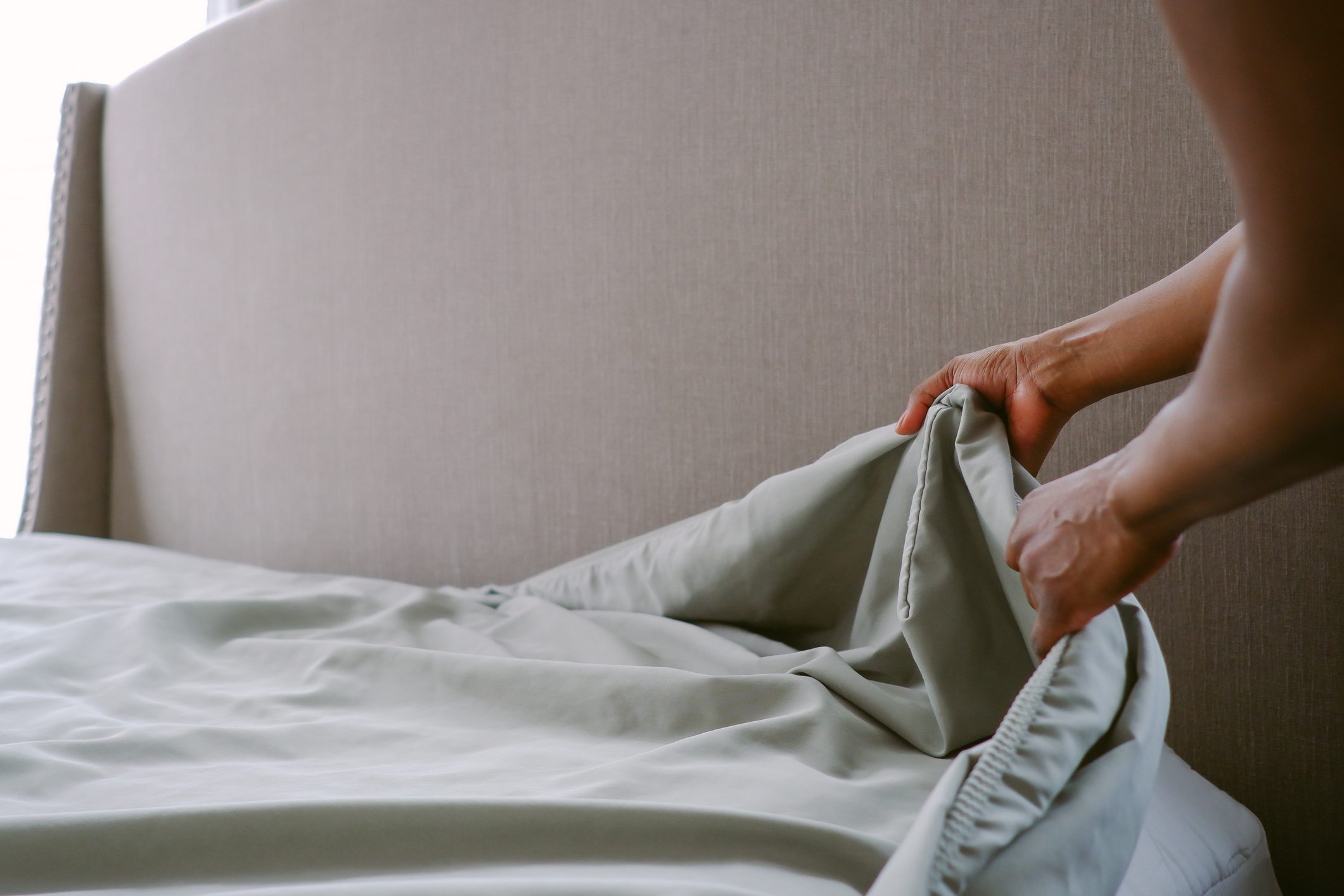 Woman Puts Sheet on Bed