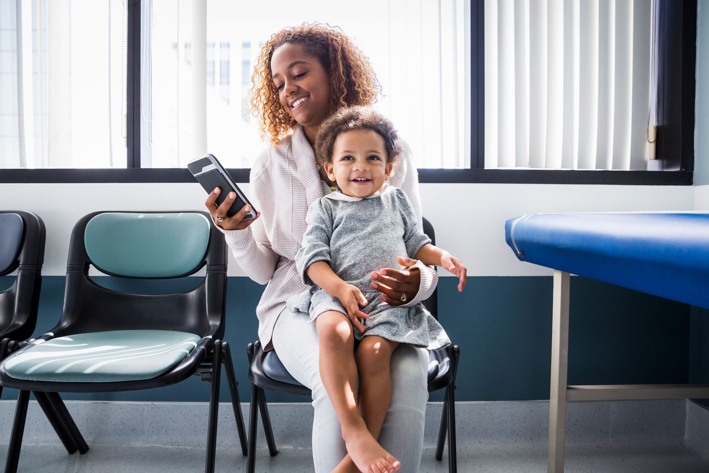 woman with kid talking on her phone while at the doctor's