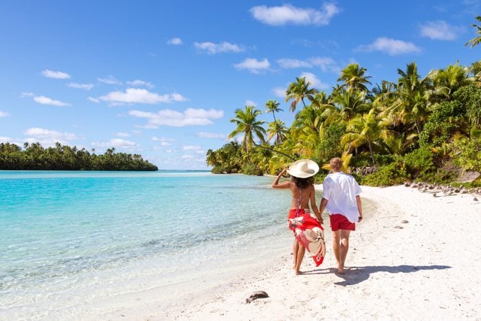 Tourist Couple Hand In Hand Walking On Beach