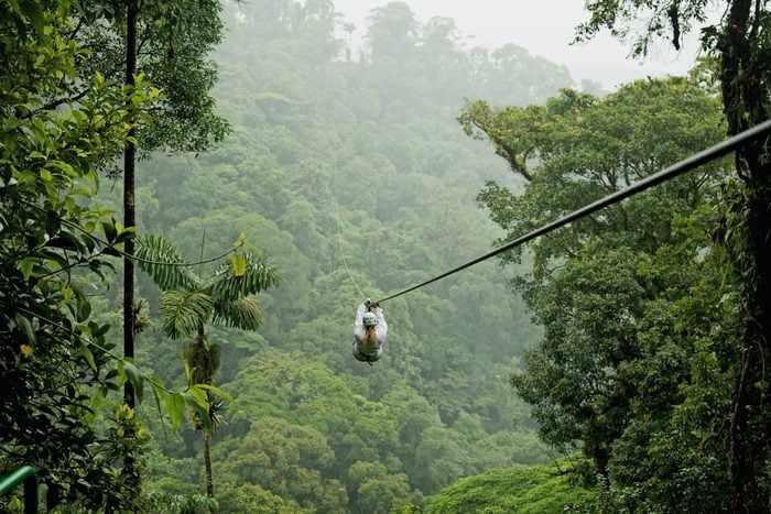 A Person Zip Lining Above A Forest In Costa Rica.