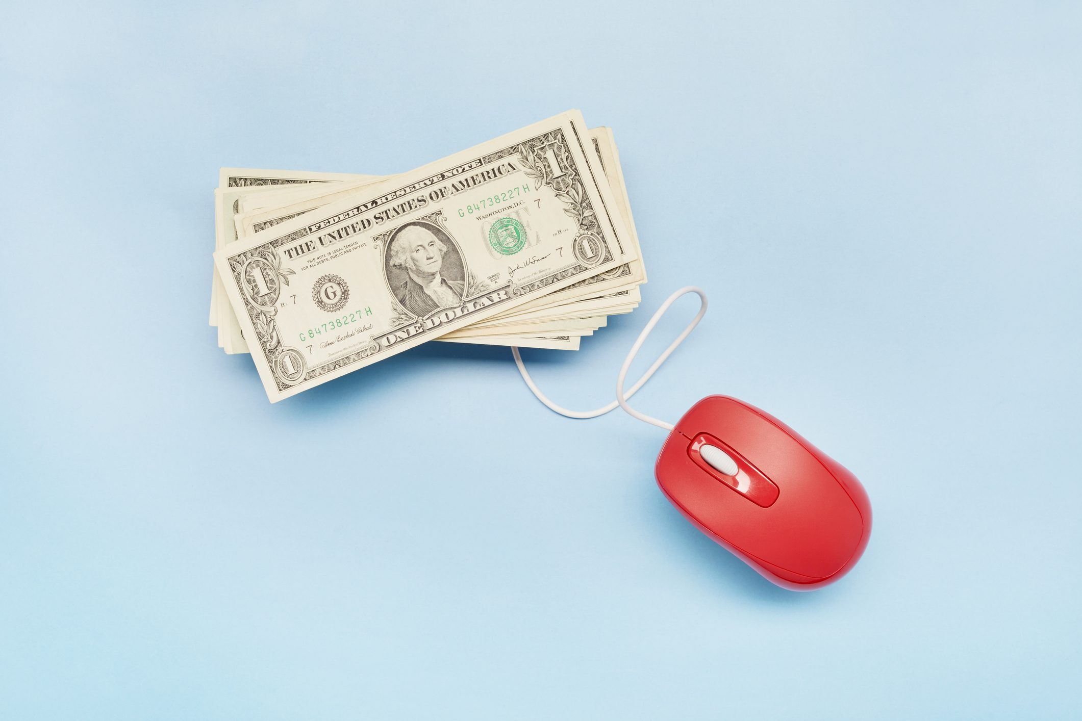 High angle view of American Dollar banknotes and computer mouse on blue background