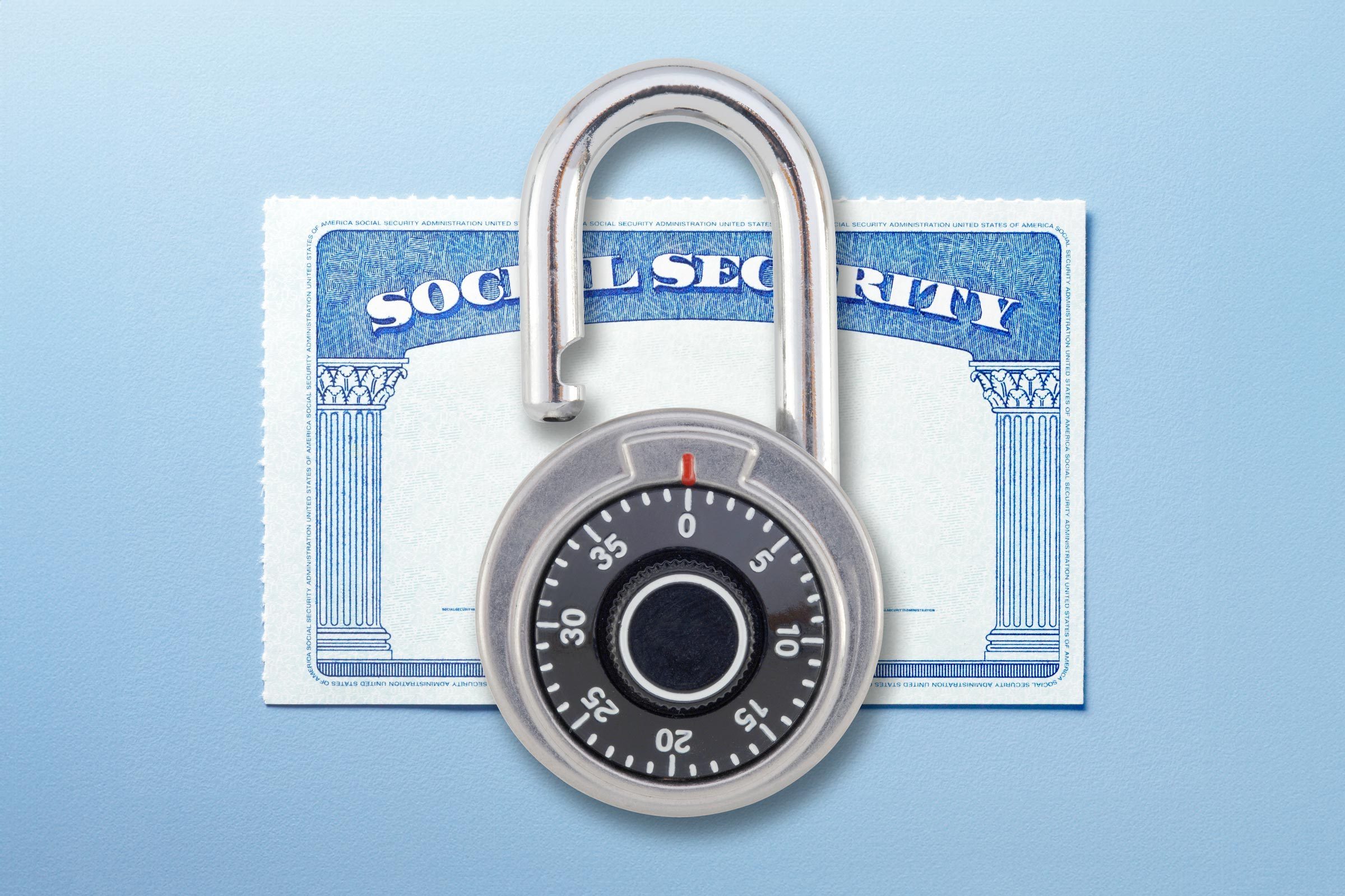 unlocked padlock with combinations on top of a social security card on a blue background