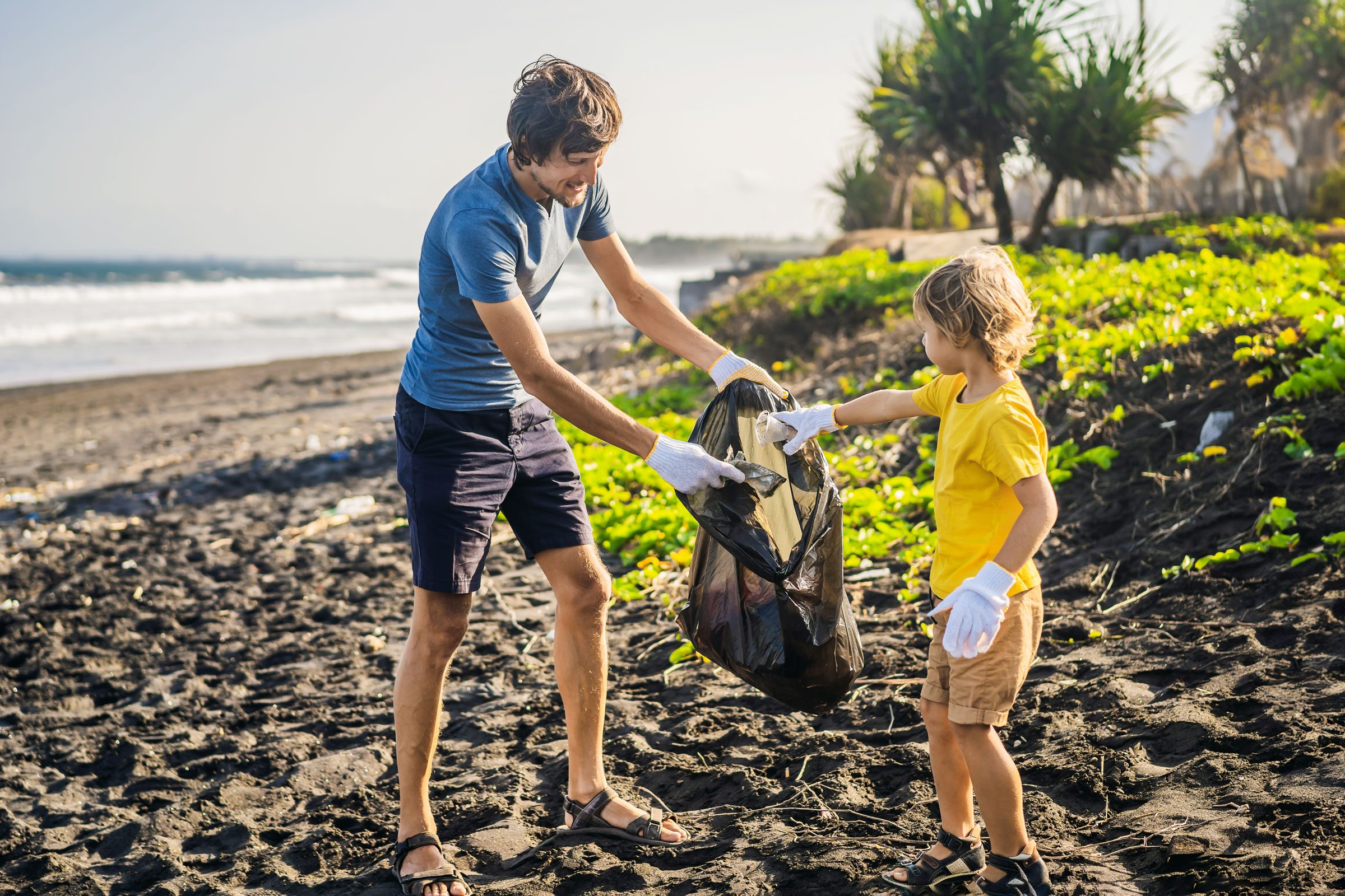 father and son picking up garbage on the beach