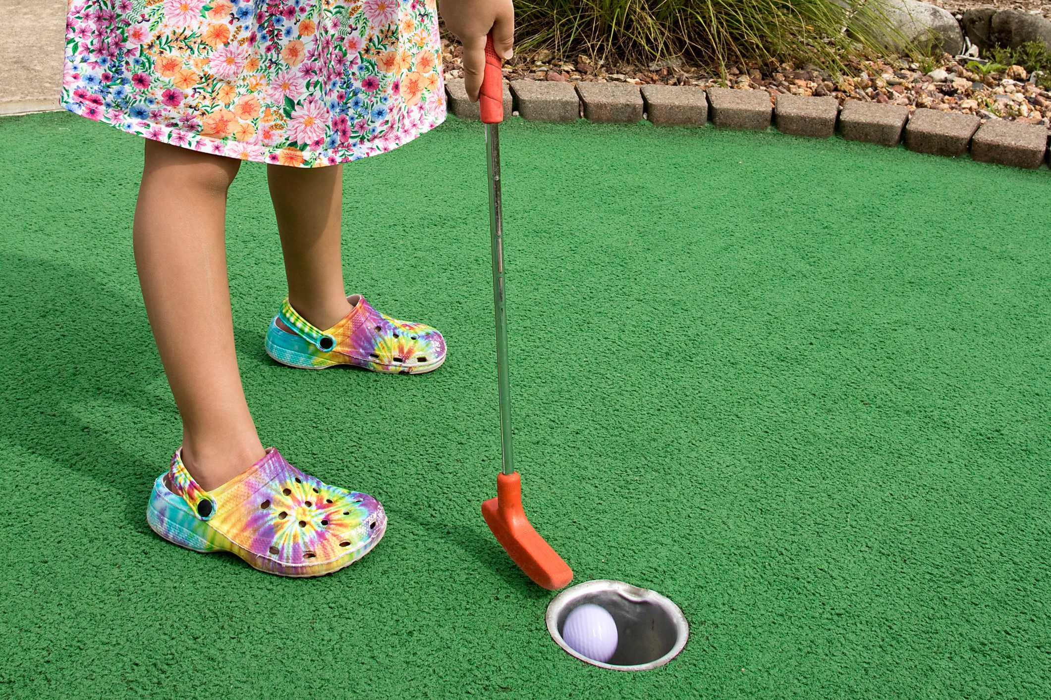 Little girl putting at mini golf. It’s in the Hole