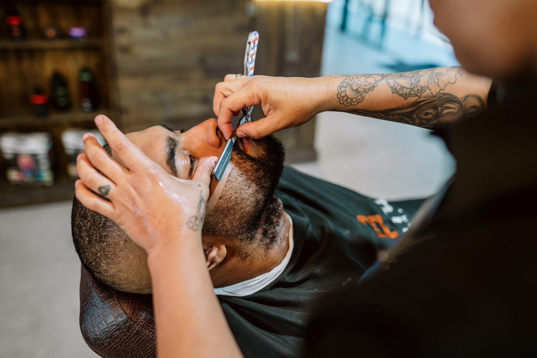Barber using a razor to trim a customer's beard in a barber shop