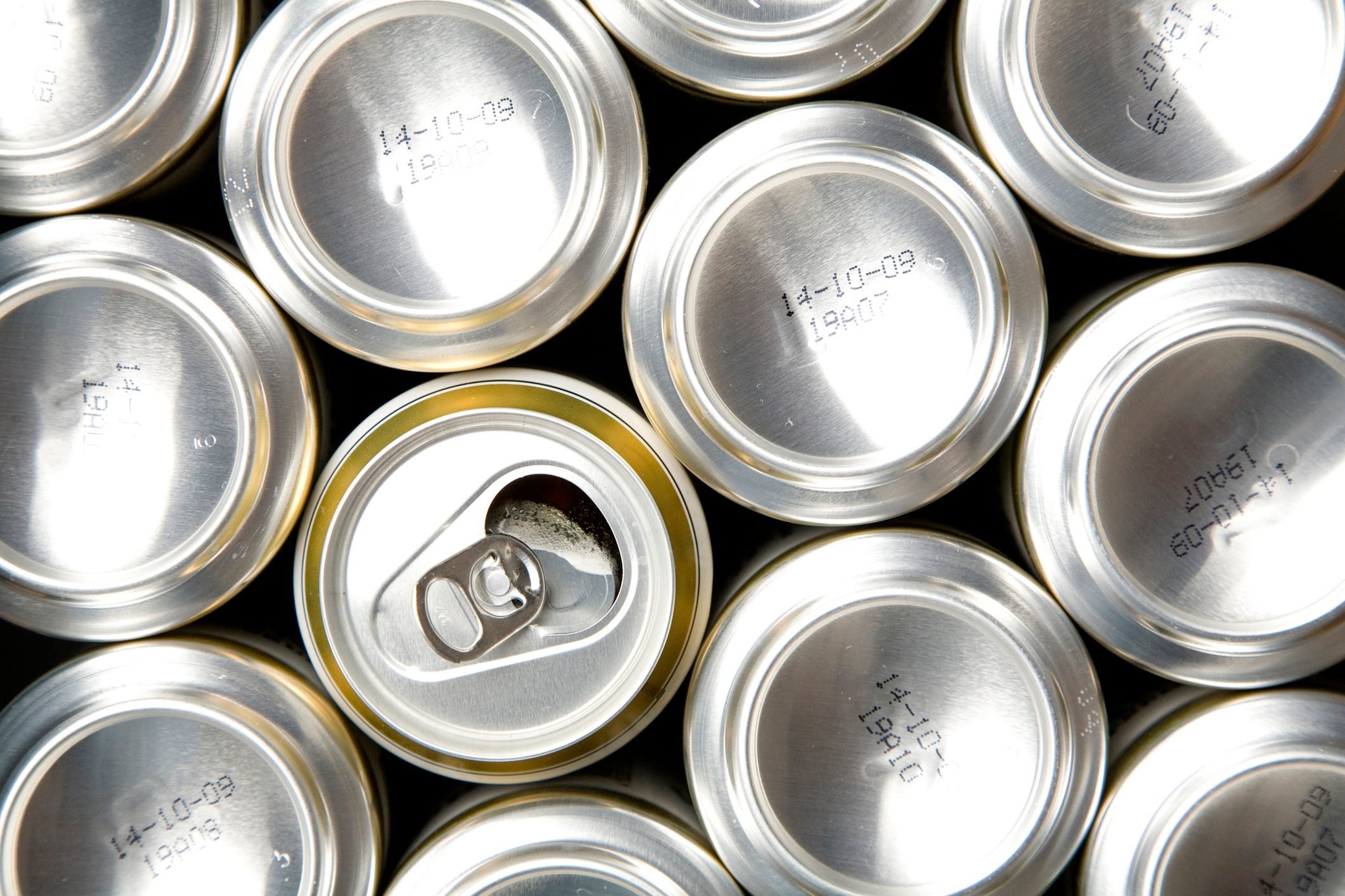 Row of soda cans with one opened can