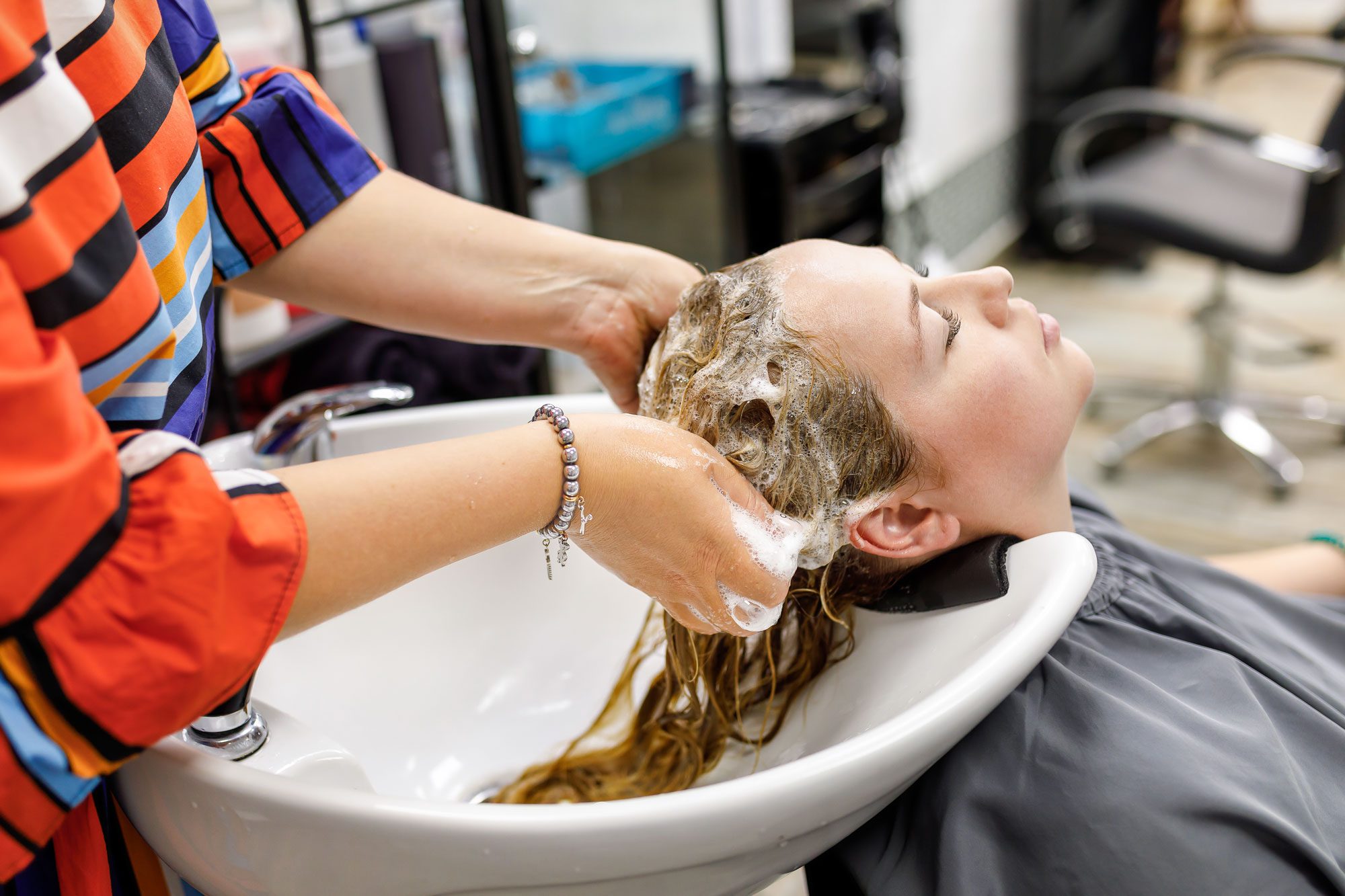 Professional Hairdresser Washes Hair To Her Client Lady Is Sitting With Her Eyes Closed