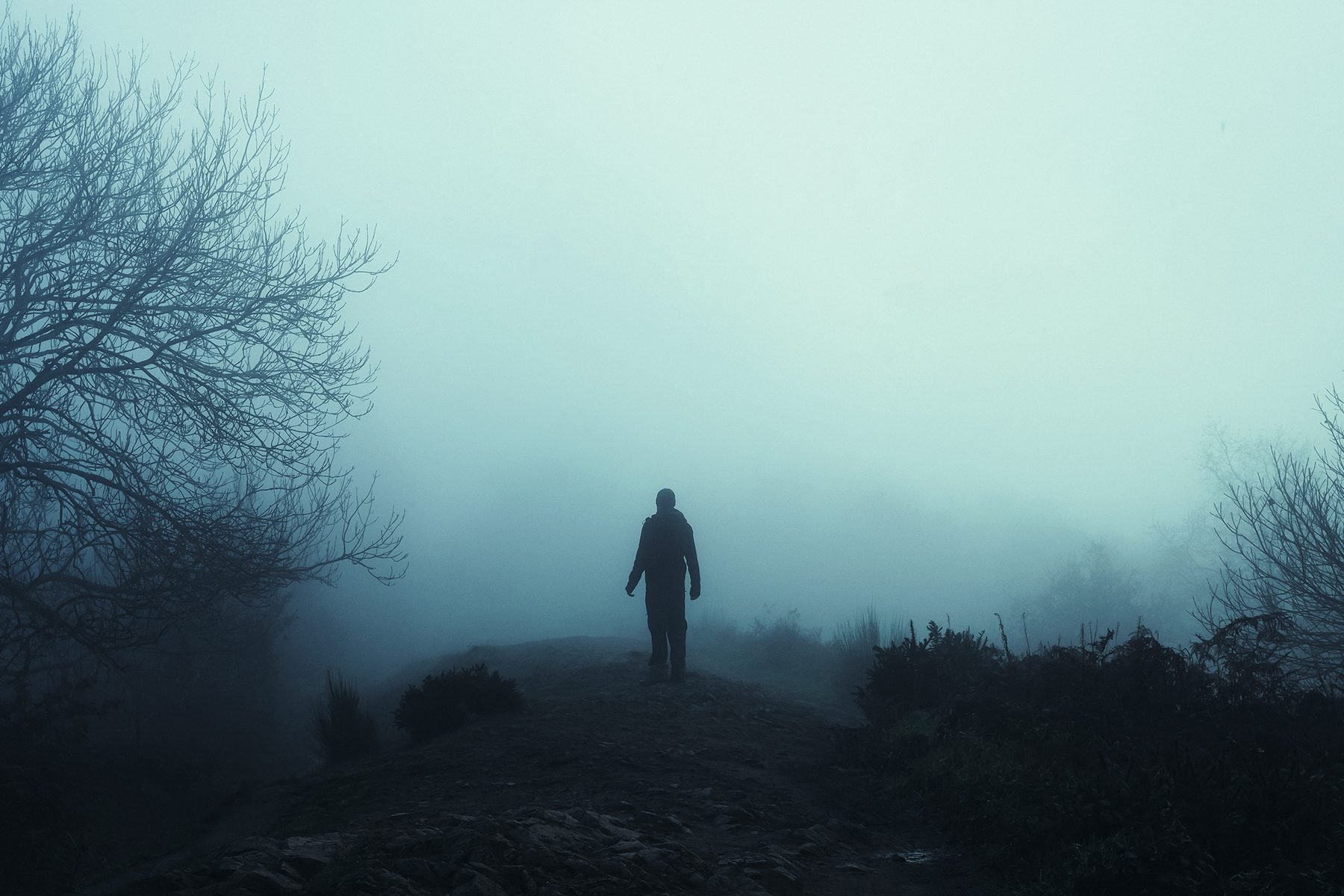 A man looking up at mysterious floating figures in the sky. On a spooky foggy, winters day in the countryside