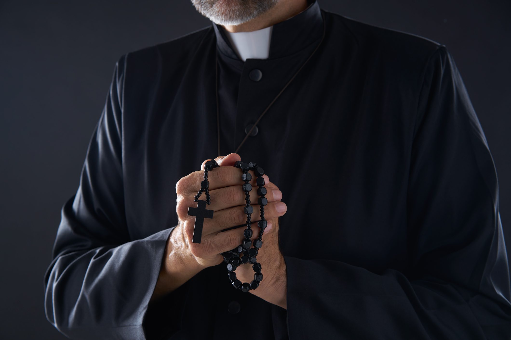 Priest praying hands with rosary beads