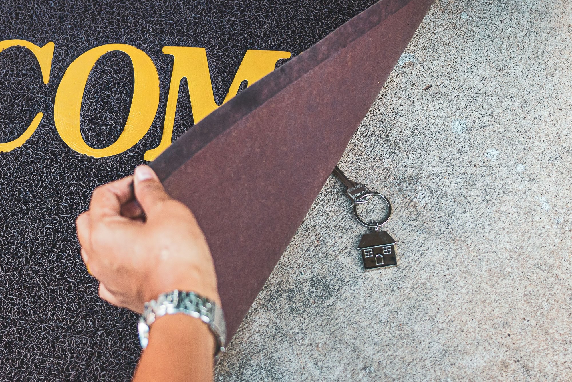 Woman Revealing Hidden Key Under Doormat